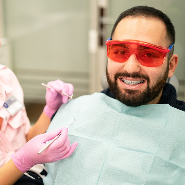 Joven mujer dentista médico y paciente sonriendo a la cámara en la clínica dental