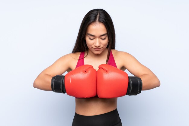 Joven mujer deporte indio en la pared azul con guantes de boxeo