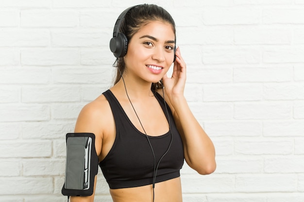 Joven mujer deportiva árabe escuchando música