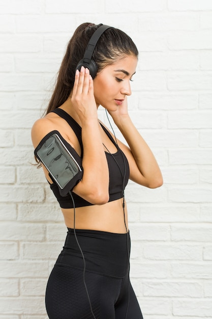 Joven mujer deportiva árabe escuchando música