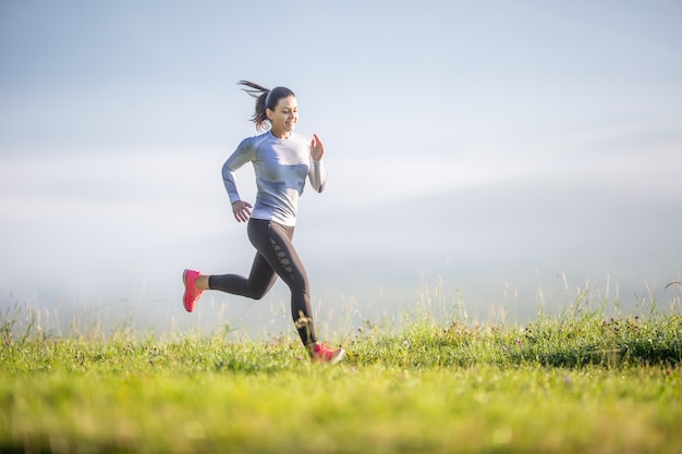 Joven mujer deportiva corriendo en la naturaleza. Deportista de entrenamiento matutino.