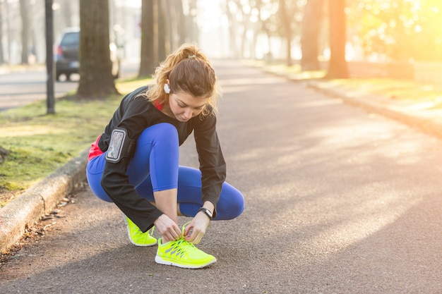 Joven mujer deportiva haciendo sus zapatos antes de correr.