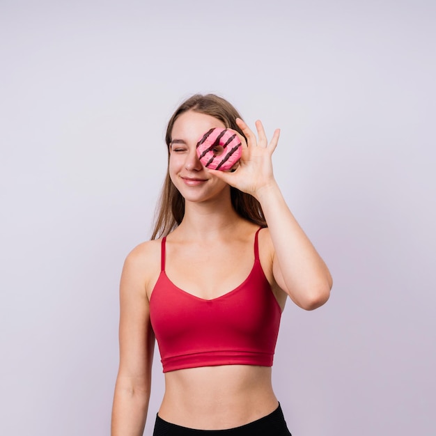 Foto joven mujer deportiva linda comiendo un pastel de rosquilla en el fondo del estudio