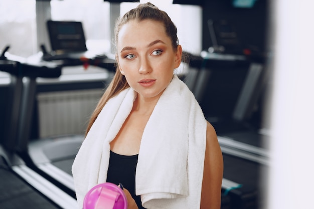Joven mujer deportiva tomando una copa en un gimnasio después del entrenamiento
