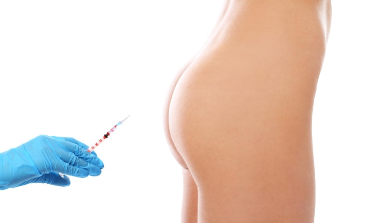 Foto joven mujer desnuda y la mano del médico con jeringa en primer plano de fondo blanco