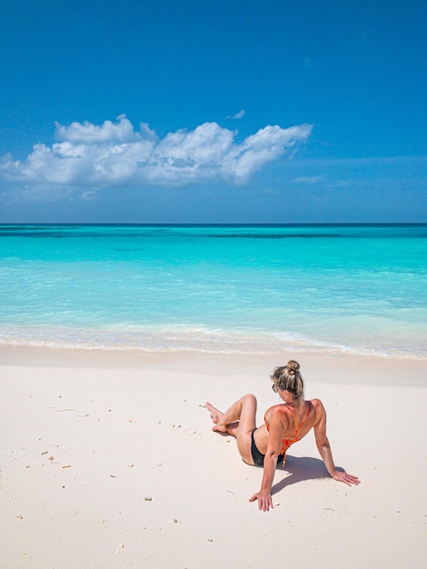 Joven mujer despreocupada relajándose en una hermosa playa exótica, paisaje marino, libertad tropical