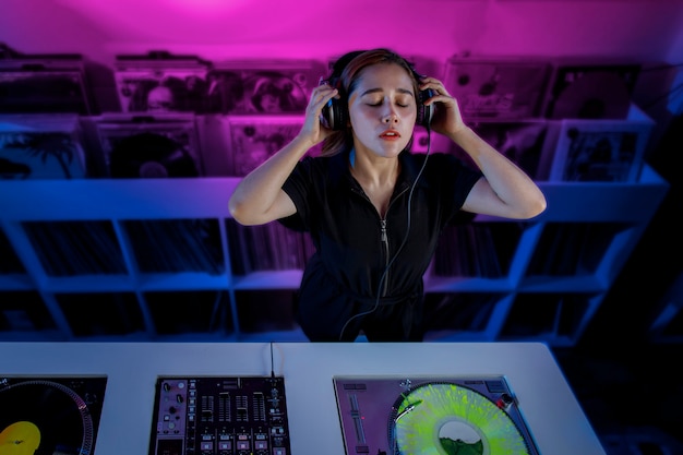 Joven mujer dj latina mezclando musica en una tienda de discos de vinilo