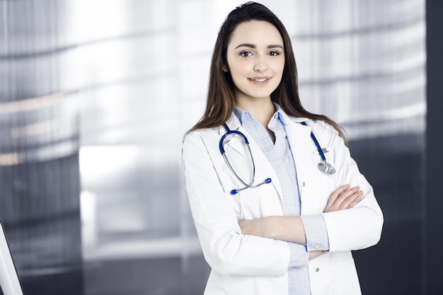 Joven mujer doctora sonriente está de pie con los brazos cruzados en una oficina de la clínica Retrato de una mujer médica amigable Servicio médico perfecto en un hospital Concepto de medicina