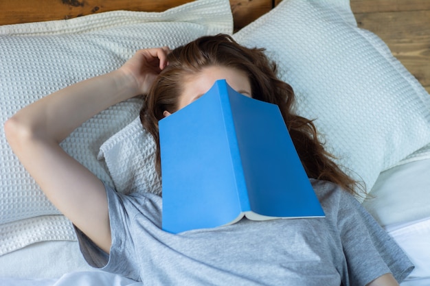 Joven mujer durmiendo en la cama con el libro