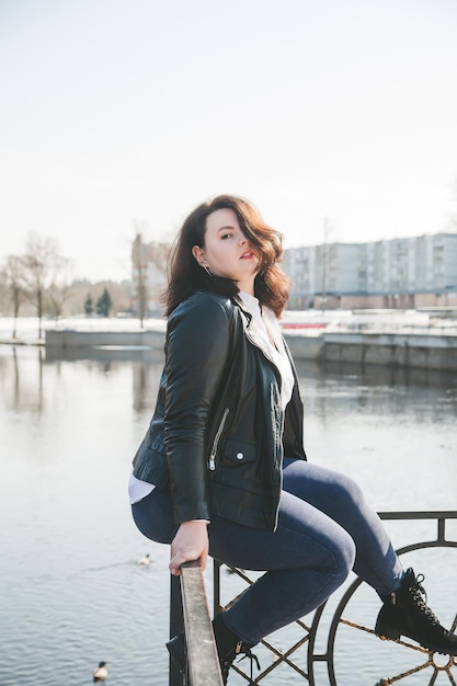 Joven mujer elegante con chaqueta de cuero caminando por las calles de la ciudad en primavera