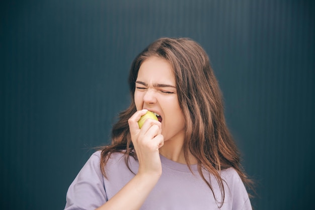 Joven mujer elegante morder el trozo de manzana verde blanca