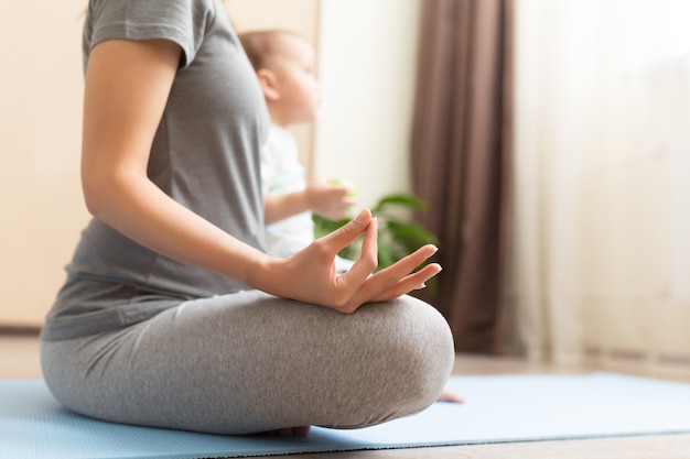 Joven mujer embarazada asiática meditando en casa con su hijo niño. Concepto de maternidad saludable