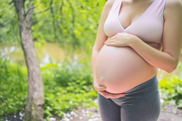 joven mujer embarazada con gran barriga en el parque al aire libre