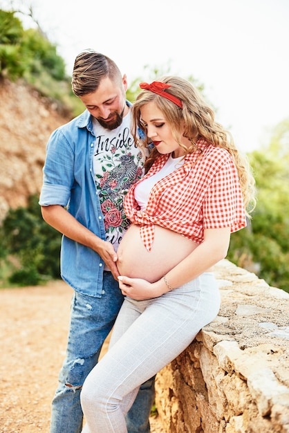 Joven mujer embarazada posando con su esposo en un parque