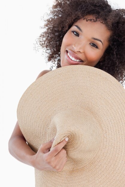 Joven mujer escondiendo su cuerpo detrás de un sombrero de paja