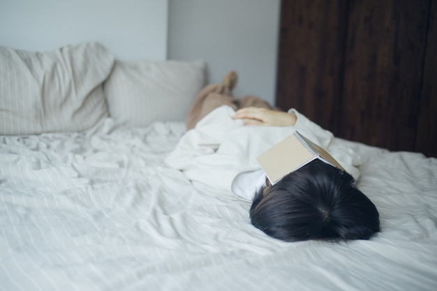 Joven mujer está durmiendo después de leer el libro en su día libre.