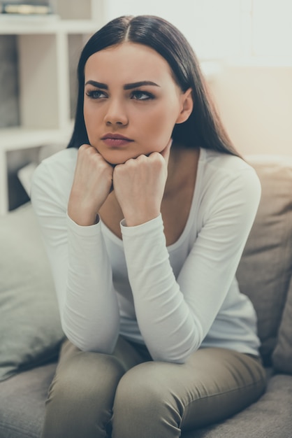 joven mujer está sentada tristemente en el sofá