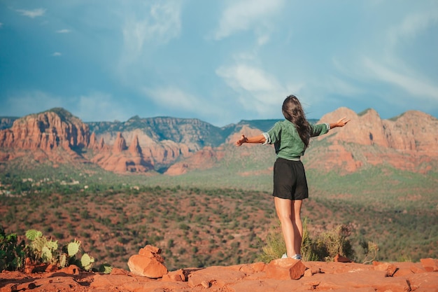 Joven mujer excursionista en el borde de un acantilado en Cathedral Rock en Sedona Arizona Vista desde Scenic Cathedral Rock en sedona con cielo azul en Arizona