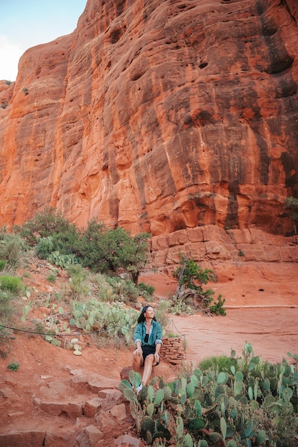 Joven mujer excursionista en el borde de un acantilado en Cathedral Rock en Sedona Arizona Vista desde Scenic Cathedral Rock en sedona con cielo azul en Arizona