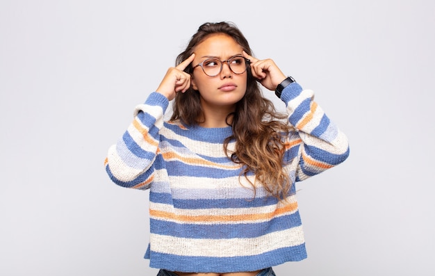 Foto joven mujer expresiva con gafas posando en la pared blanca