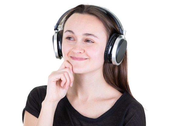 Joven mujer feliz con auriculares escucha música con la mano en la barbilla