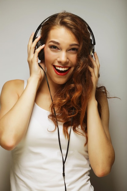 Joven mujer feliz con auriculares escuchando música