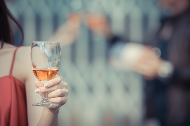 Joven mujer feliz bebiendo sosteniendo y bebiendo un vaso de alcohol en el bar nocturno o en el club nocturno