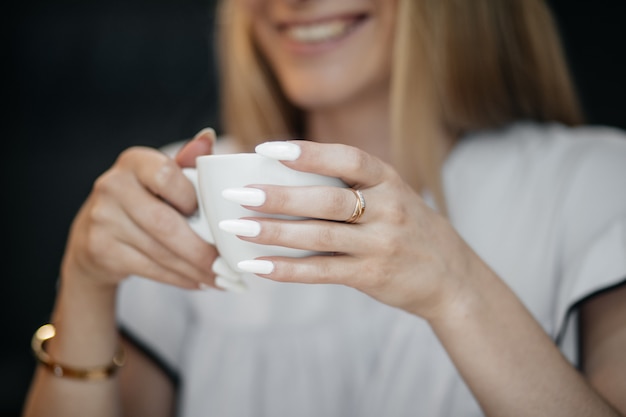 Joven mujer feliz bebiendo té verde en un café