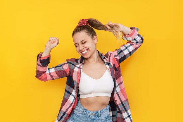 Una joven mujer feliz con una camisa a cuadros y jeans está feliz por las noticias o por ganar la lotería