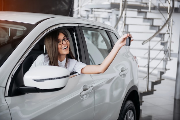 Joven mujer feliz cerca del coche con llaves en mano