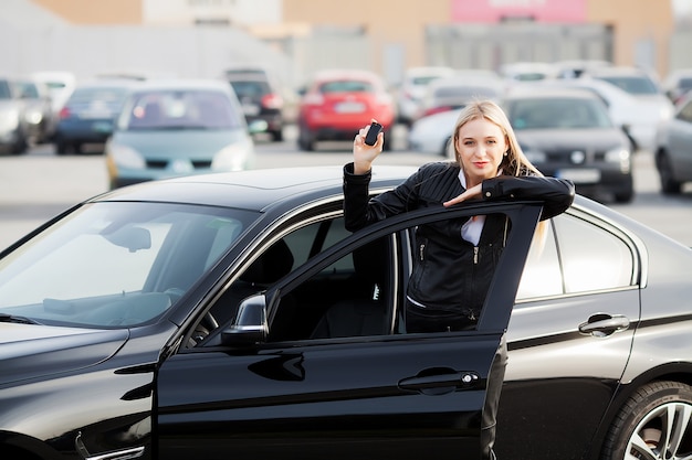 Joven mujer feliz compró nuevo coche moderno.