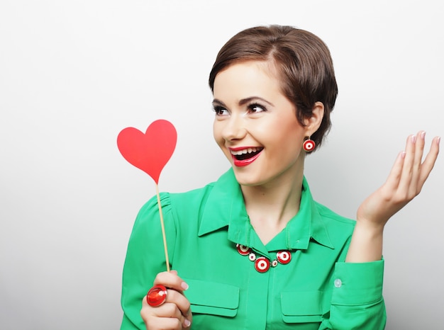 Joven mujer feliz con corazón de papel rojo