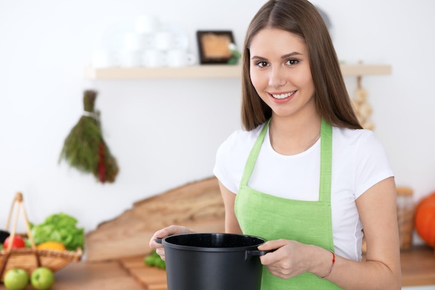 Foto joven mujer feliz en un delantal verde cocinando en la cocina ama de casa encontró una nueva receta para su sopa comida saludable y concepto vegetariano