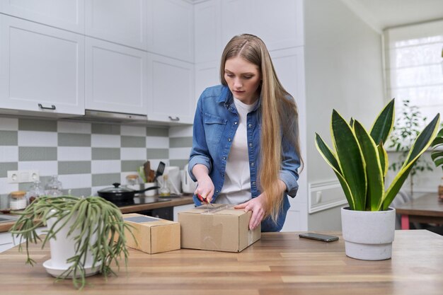 Joven mujer feliz desempaquetando cajas de cartón unboxing esperado paquete postal