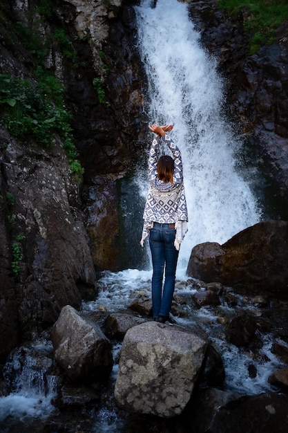 Joven mujer feliz disfrutando de la cascada de verano