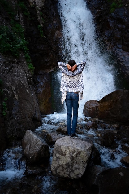 Joven mujer feliz disfrutando de la cascada de verano