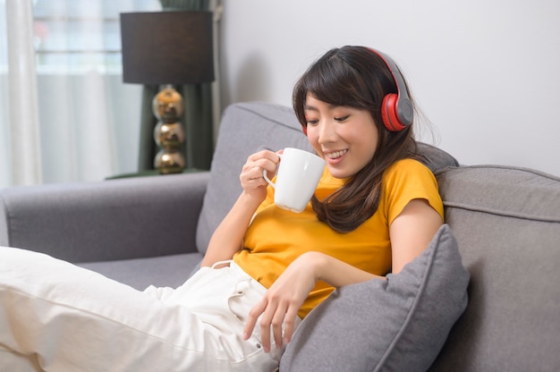 Una joven mujer feliz escuchando música y relajándose en casa