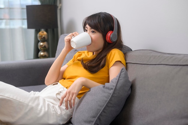 Una joven mujer feliz escuchando música y relajándose en casa