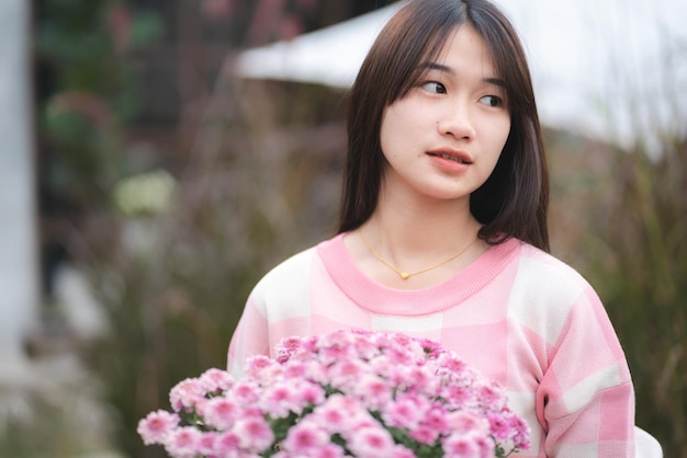 Joven mujer feliz persona sonriendo con flor rosa floreciendo bastante lindo retrato de niña en verano con planta de flor natural en color rosa y colorido natural al aire libre