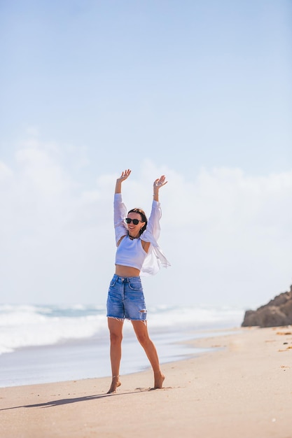 Joven mujer feliz en la playa disfruta del viento