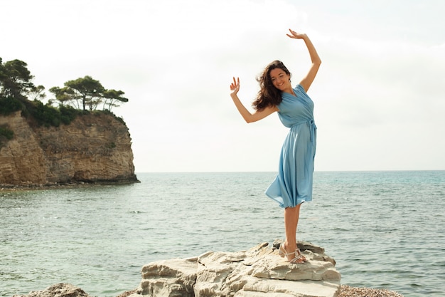 Joven mujer feliz posando cerca del mar