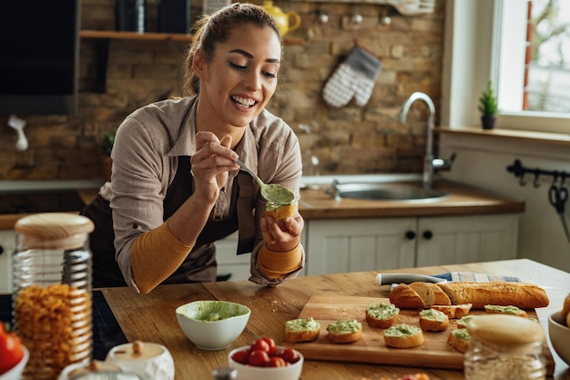 Joven mujer feliz preparando bruschetta saludable en la cocina