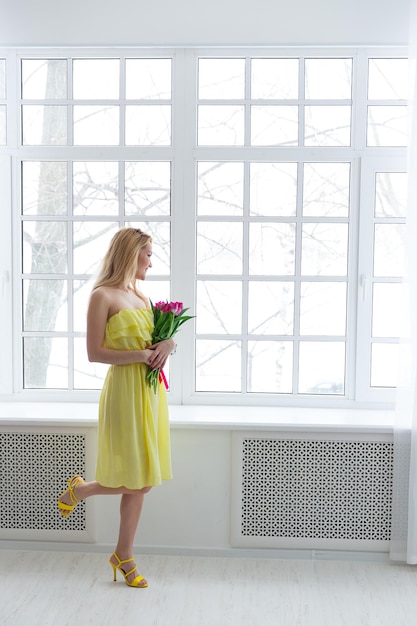 Foto joven mujer feliz con ramo de tulipanes en vestido amarillo 8 de marzo día internacional de la mujer