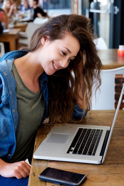 Joven mujer feliz sentado en el café con el cuaderno