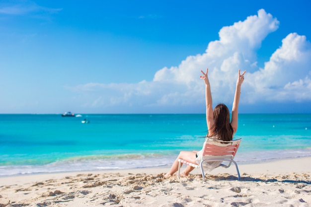 Joven mujer feliz en una silla de playa en vacaciones de verano