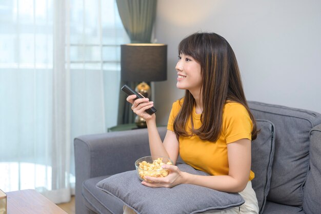 Una joven mujer feliz viendo una película y relajándose en casa