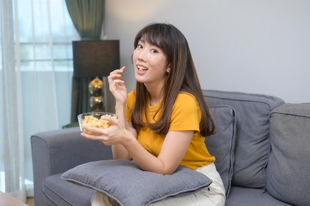 Una joven mujer feliz viendo películas y relajándose en casa