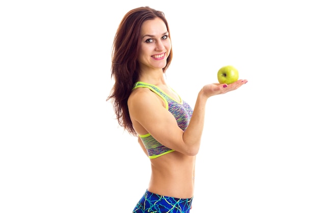 Joven mujer feliz vistiendo top deportivo de colores y leggins con manzana verde