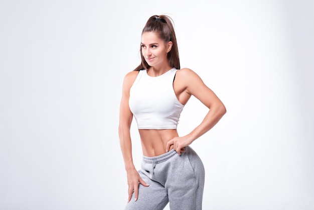 Joven mujer fitness blanca con ropa deportiva de pie sobre fondo de pared blanca Concepto de fitness