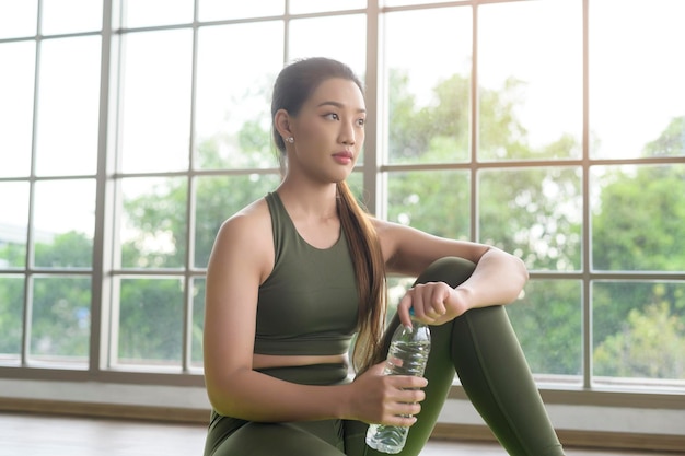 Joven mujer fitness en ropa deportiva bebiendo agua después de hacer ejercicio en casa Saludable y estilos de vida